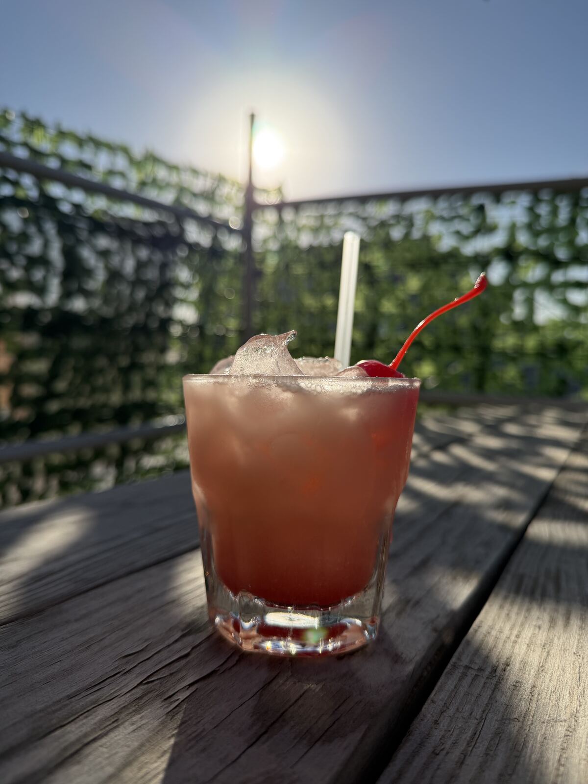 Cocktail with a cherry garnish on the patio at sunset