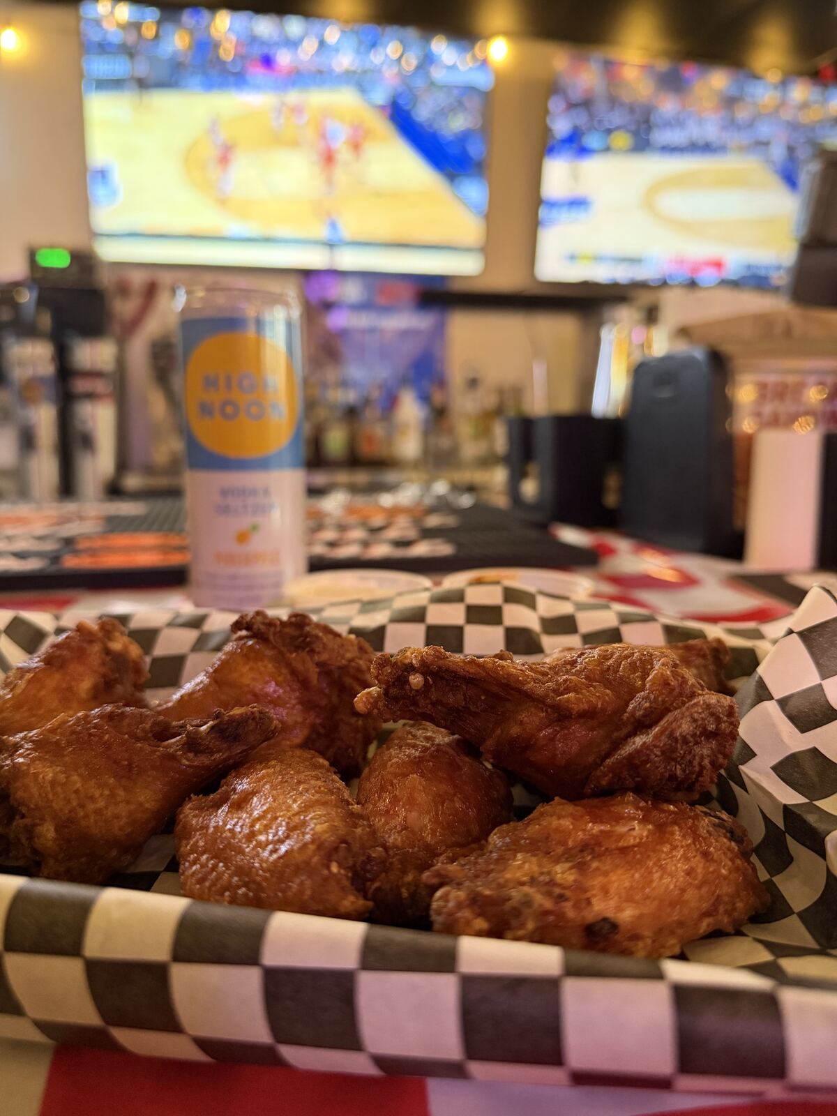 Chicken wings with a High Noon seltzer, basketball on TV